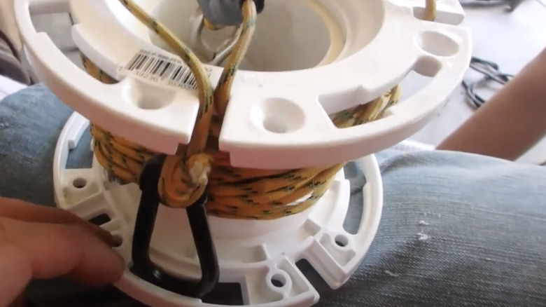 A magnet fishing rope and tackle set wrapped around the spool from an old garden hose reel.