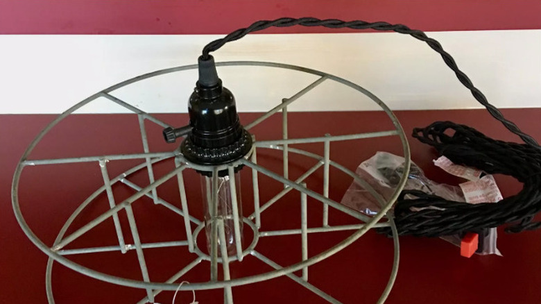 An old metal garden hose reel is transformed into a hanging light fixture for indoors.