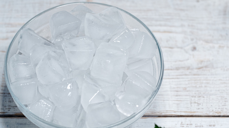 Bowl of ice cubes on wooden table