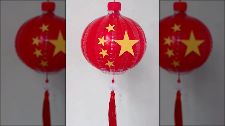 Red lantern with stars on it made from a red balloon, plastic bottle, and golden stars