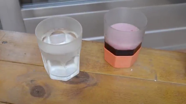 Two glasses on a wooden table, one has a balloon on the bottom to mark the glass