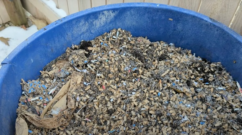 Bright blue bucket full of dirt and cardboard scraps for composting