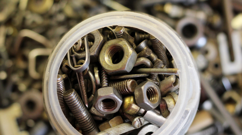 Nuts and bolts stored in an old parmesan cheese container with no lid.