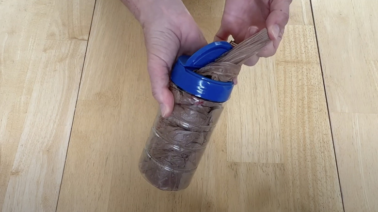 A hand pulls a plastic bag out of a parmesan cheese container.