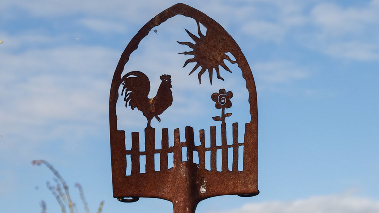 A farmhouse scene is laser or hand cut into a rusty shovel blade.