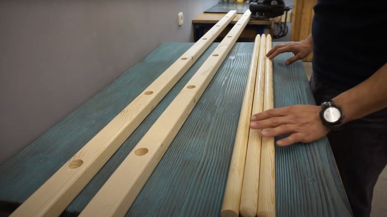 A carpenter gets ready to cut wooden shovel handles into the rungs for a ladder.
