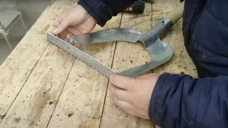 A craftsperson transforms an old shovel head into a weeder or hoe using welding and cutting.
