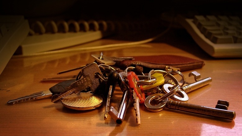 desk with a keychain with many keys on it, a round medal, and a leather pouch