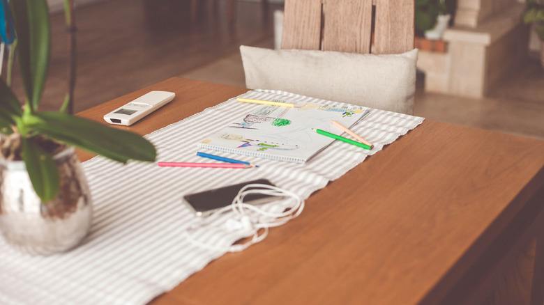 striped table runner on a wood table, with coloring pad and colored pencils.