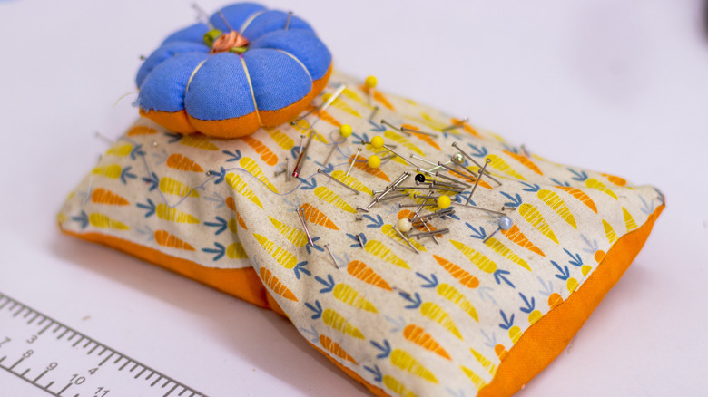 A pin cushion with carrot patterns and a raised blue and orange cushion.