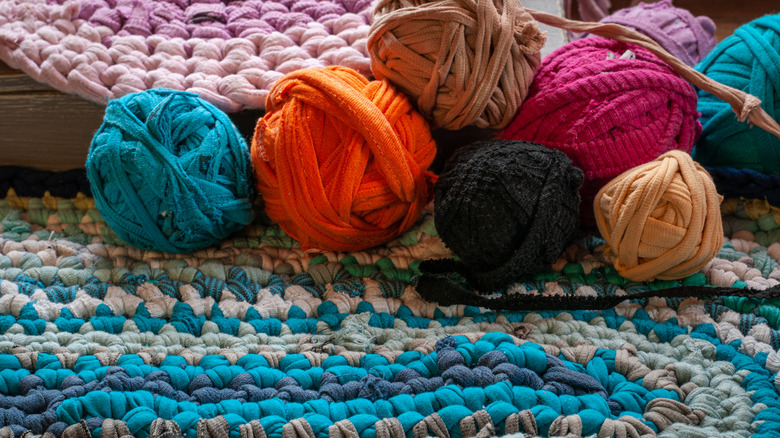 A group of brightly colored rag balls sitting on a crocheted cover.