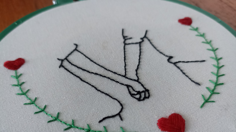 Embroidered art pattern featuring two held hands.