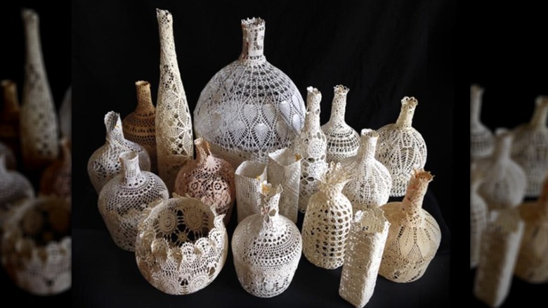Grouping of many different bottles covered in doilies