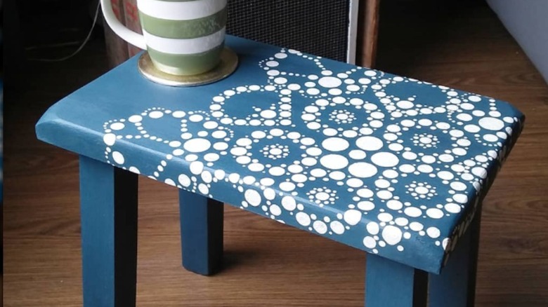Blue doily-stenciled bench with green striped mug and coaster