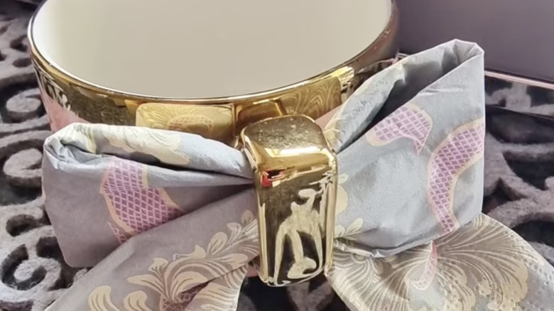 A vintage hankie tied through the handle of a gold tea cup.