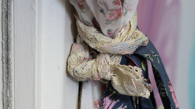 A lace-edged handkerchief and other scrap vintage fabric used as a curtain tie.