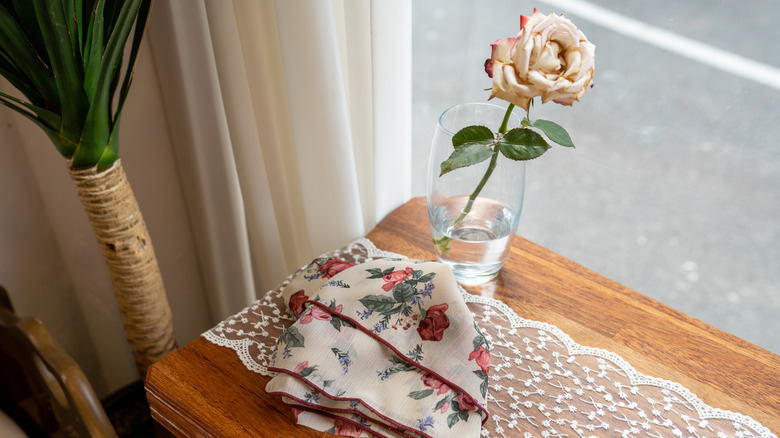 A vintage handkerchief enhances the display on a window-side table in a home.