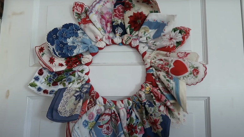 A DIY hankie wreath adorns the white front door of a house.