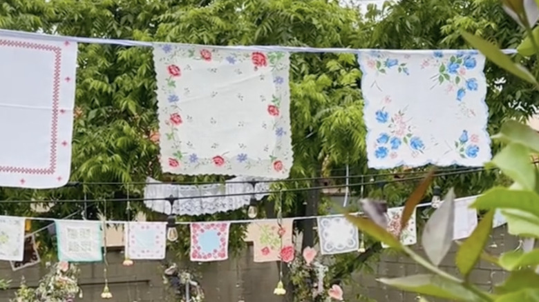 Bunting made from vintage handkerchiefs hangs across a verdant backyard with string lights.