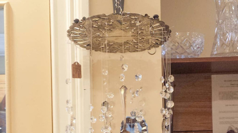 A wind chime made out of a trivet, silverware, and crystal beads
