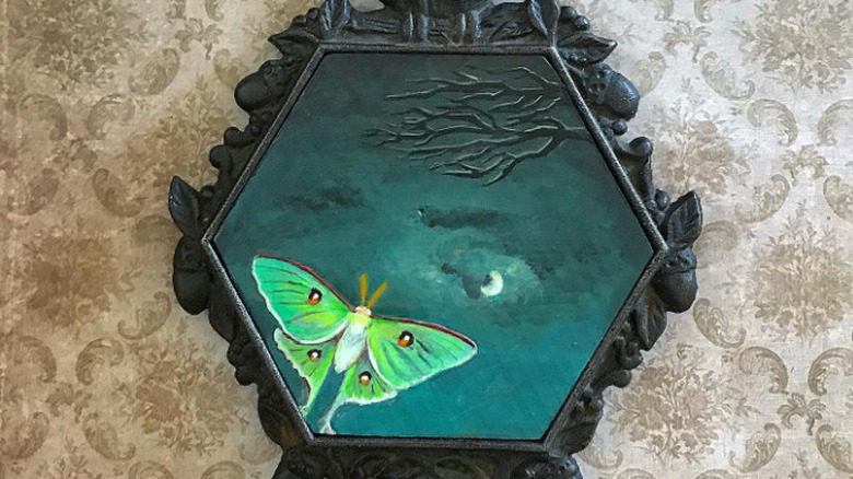 A metal trivet with a hand-painted tile insert