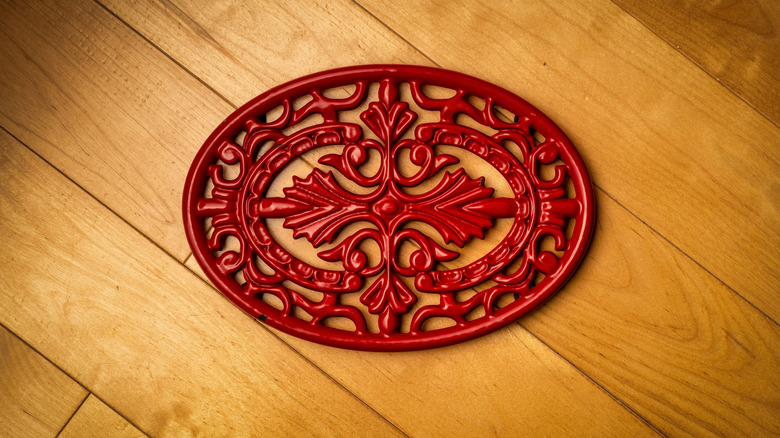 A red metal trivet on a wood surface