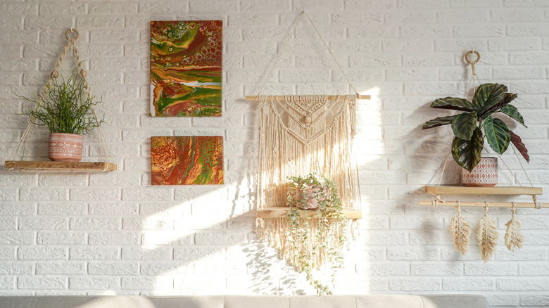 A macrame hangs from a wooden dowel on a white wall.