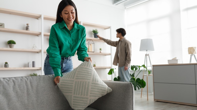 Woman arranging sofa cushions