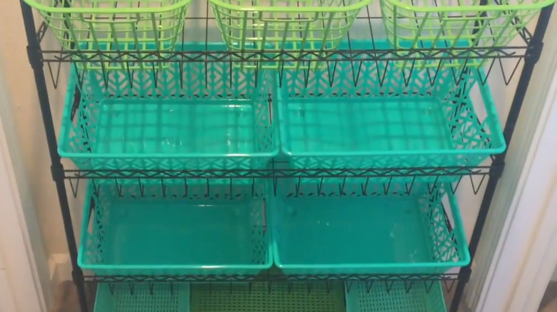 A black metal shoe rack lined with green and turquoise baskets.