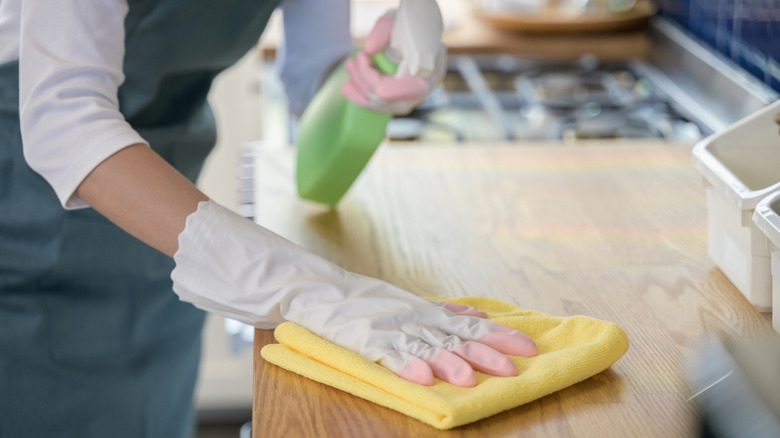 Close up of person using cleaning spray to clean kitchen