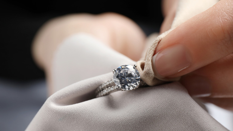 Close up of person wiping diamond ring with microfiber cloth