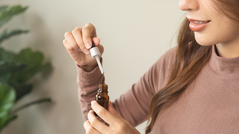 Woman holds dropper over vial