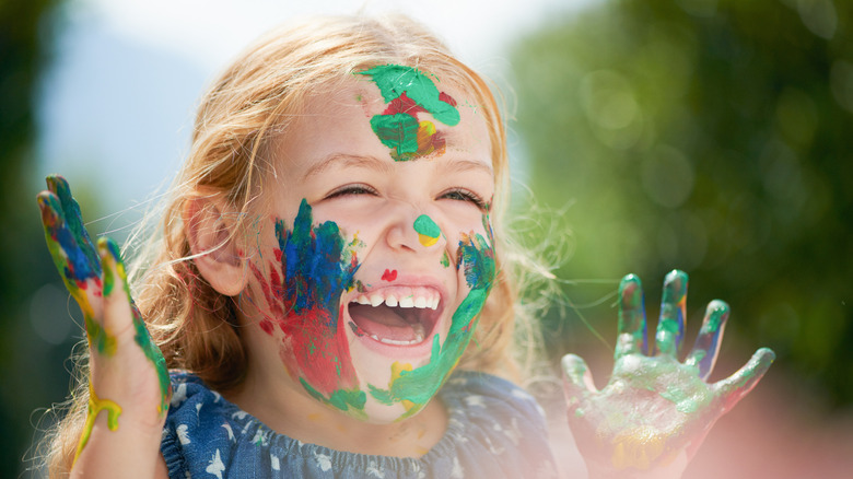 Happy little girl covered in paint