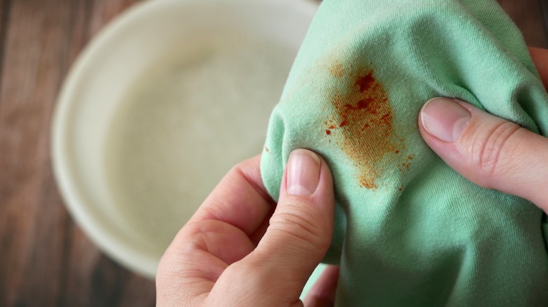 Hands holding stained green fabric