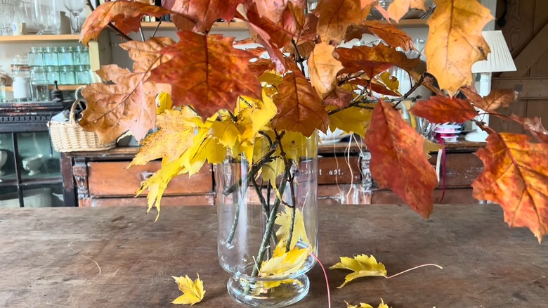 Fall leaves in a glass vase on a wood counter