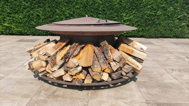 Metal fire dish with logs stacked beneath.