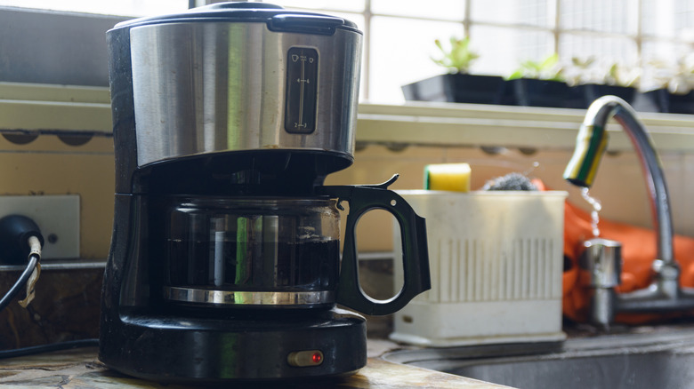 A coffee machine sitting next to a sink and tap.