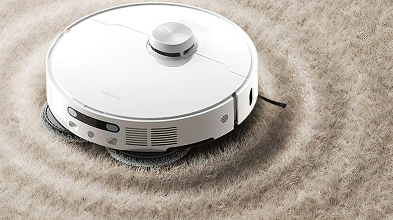 A white robot vacuum cleaning a beige carpet