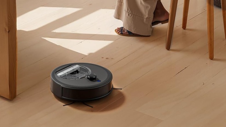 A black robot vacuum cleaning the floors of a house