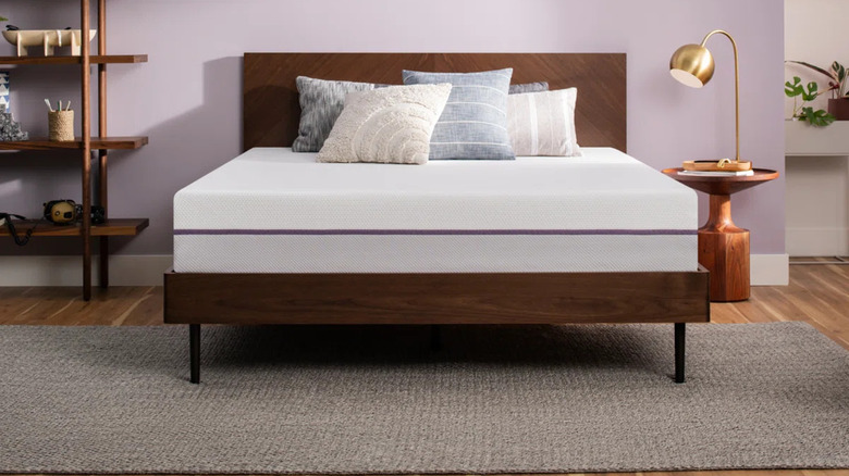The Purple Mattress on a dark wood bedframe with decor in the background