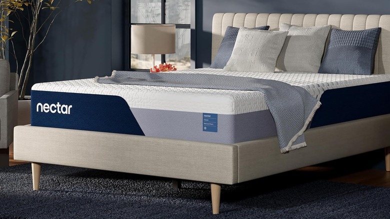 The Nectar Classic mattress on a bed frame with a blue wall in the background