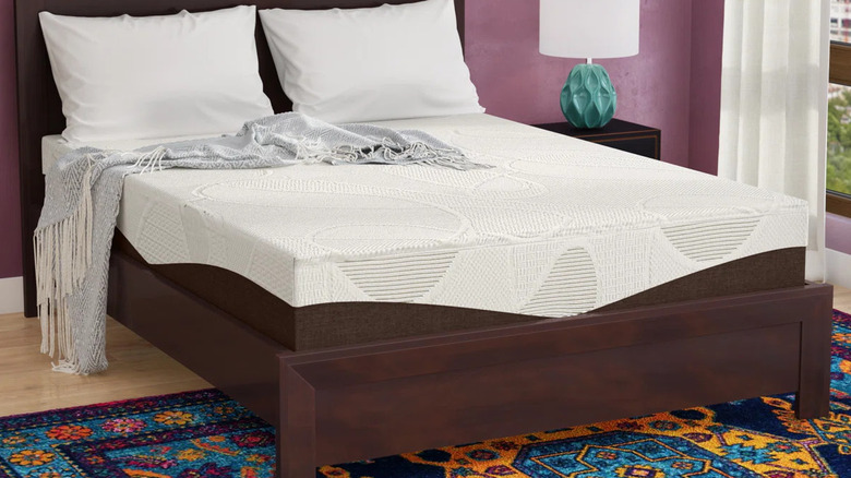 The Slumber Solutions Gel Memory Foam Mattress on a dark wood bedframe with a bright area rug