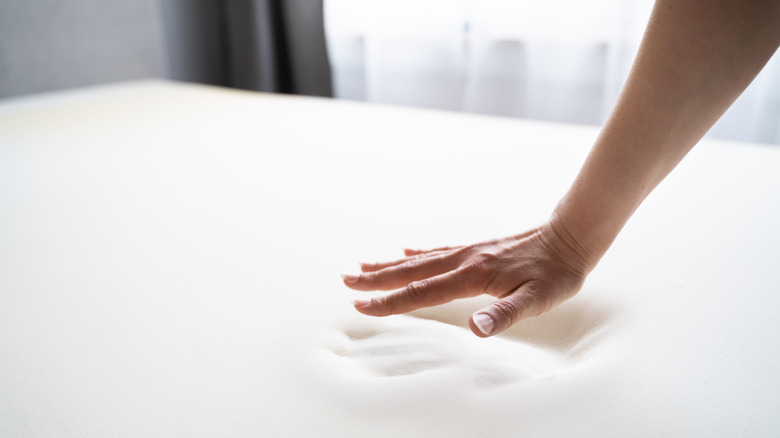 Hand pushing down on memory foam mattress