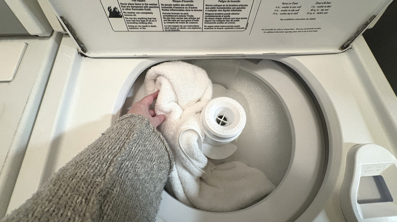 A white towel is added to a washing machine full of suds