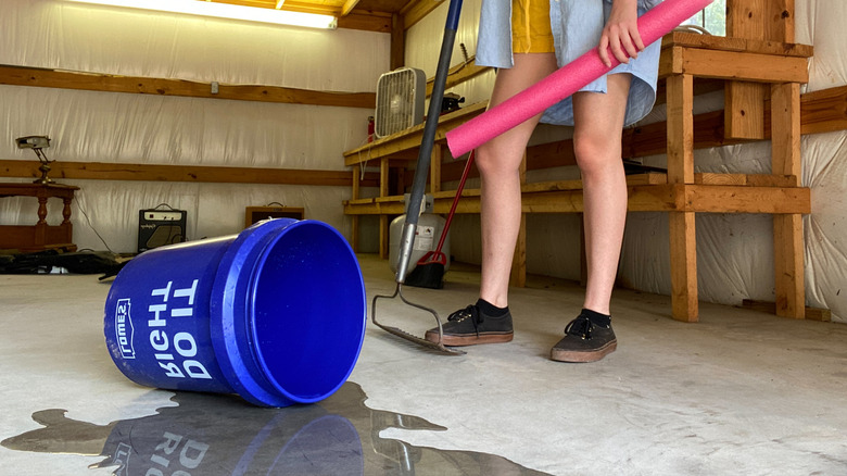 Person holding pool noodle by spilled bucket
