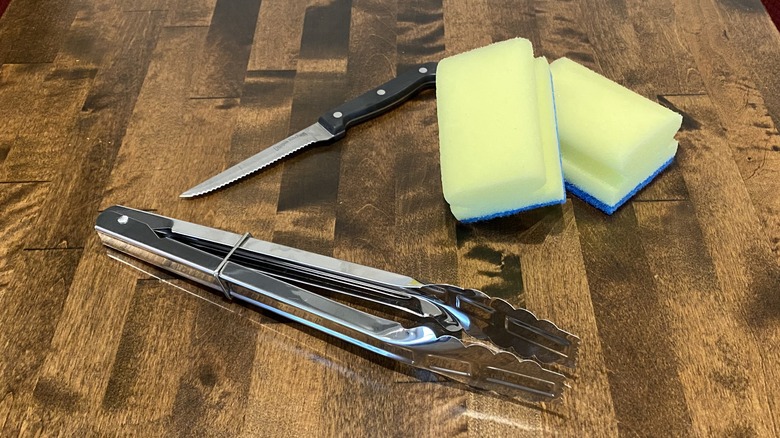 Knife, sponges, tongs on table