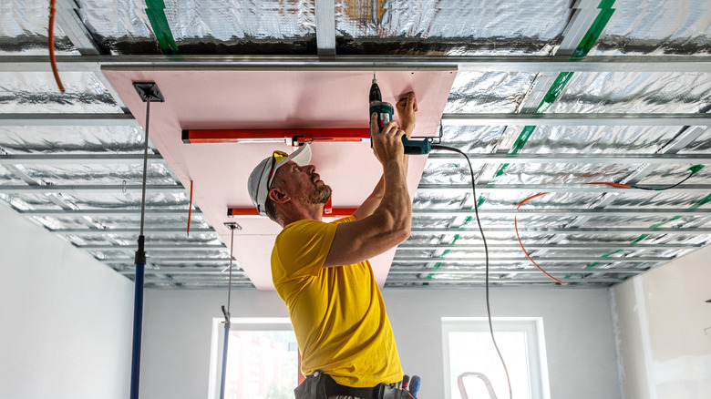 Builder putting up drywall using a drywall lift