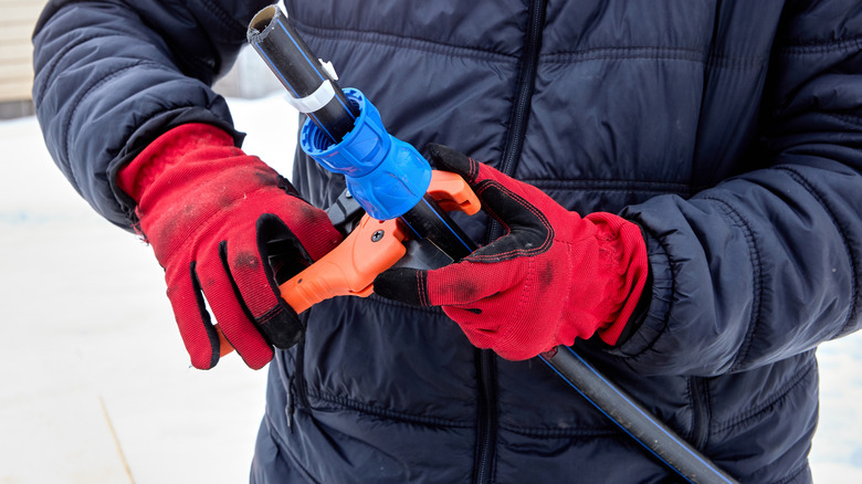 Man using a ratcheting pipe cutter outside