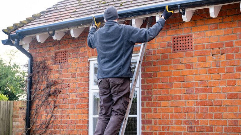 Man standing on ladder outside of his house