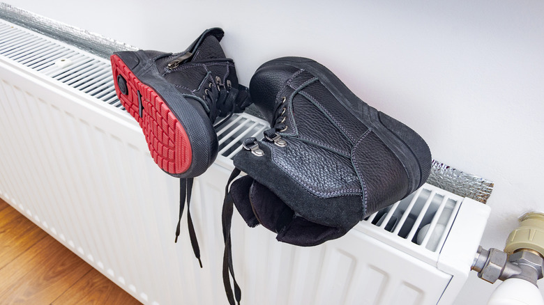 A pairs of boots drying on top of a radiator.